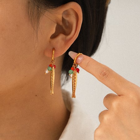 Un par de pendientes colgantes con forma de pez, de acero inoxidable color dorado. 2